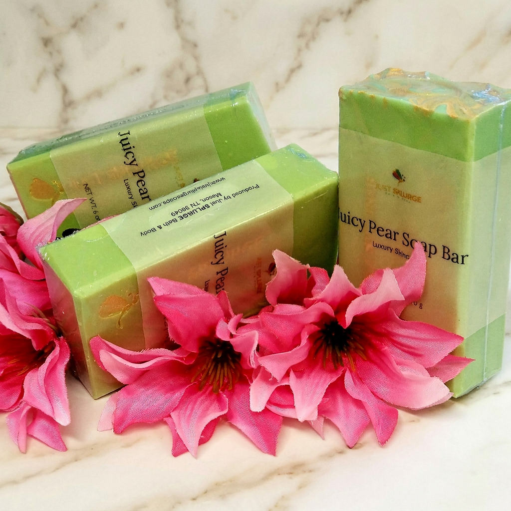 Three wrapped green Juicy Pear Soap Bars with pink flowers on warm ivory marble.