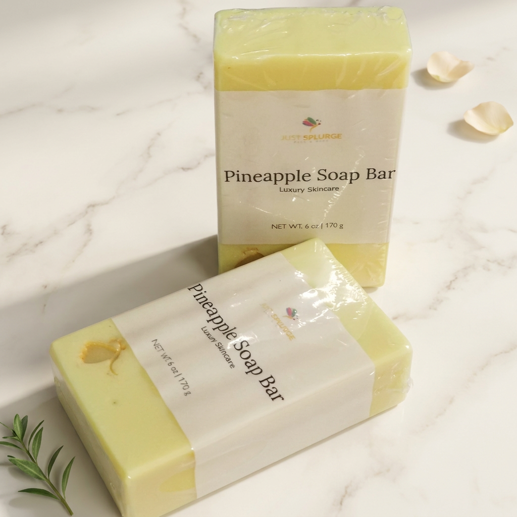 Two wrapped pale yellow Pineapple Soap Bars on warm ivory marble with cream petals and a green sprig.