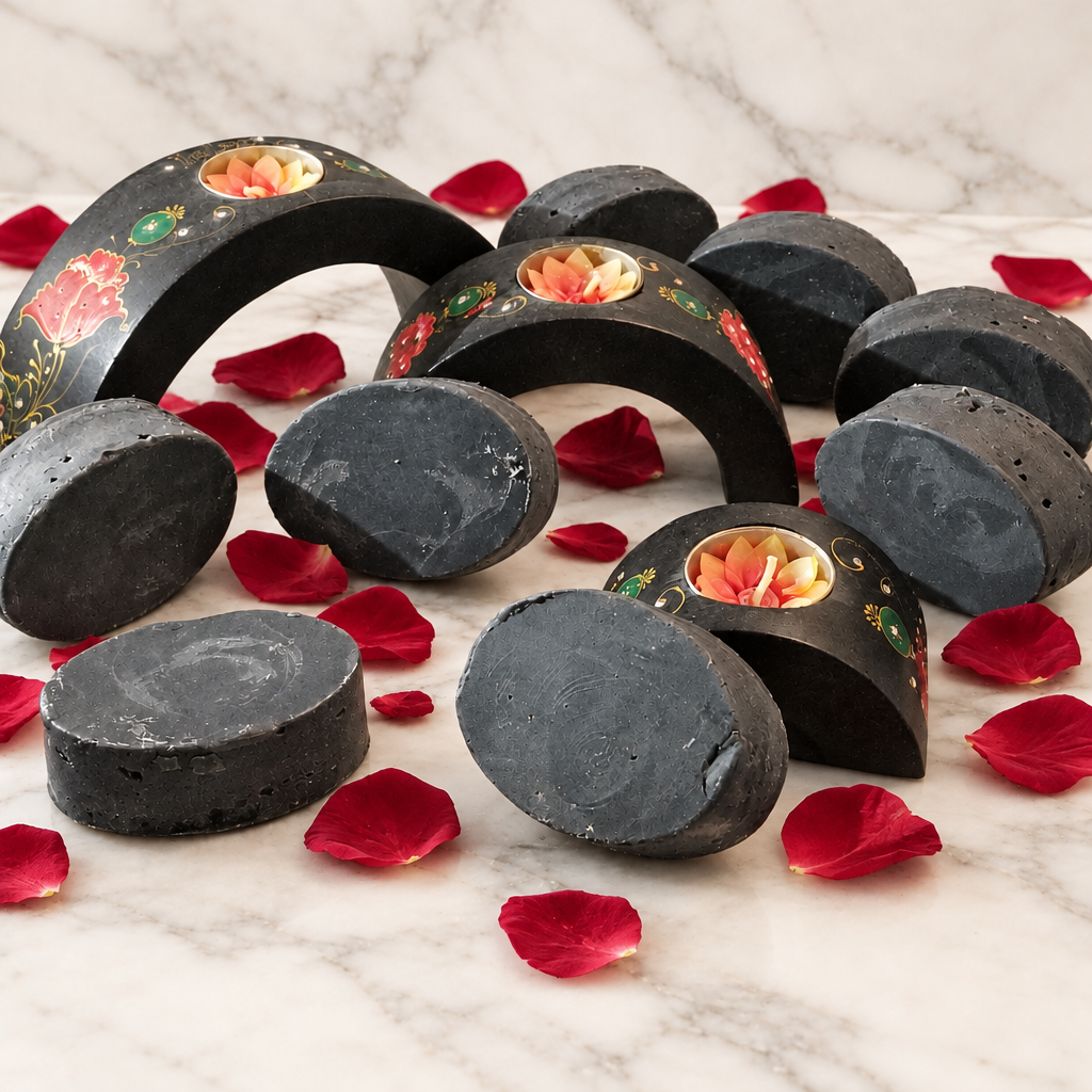Round charcoal-colored Greystone soap bars arranged on warm white marble with red rose petals.